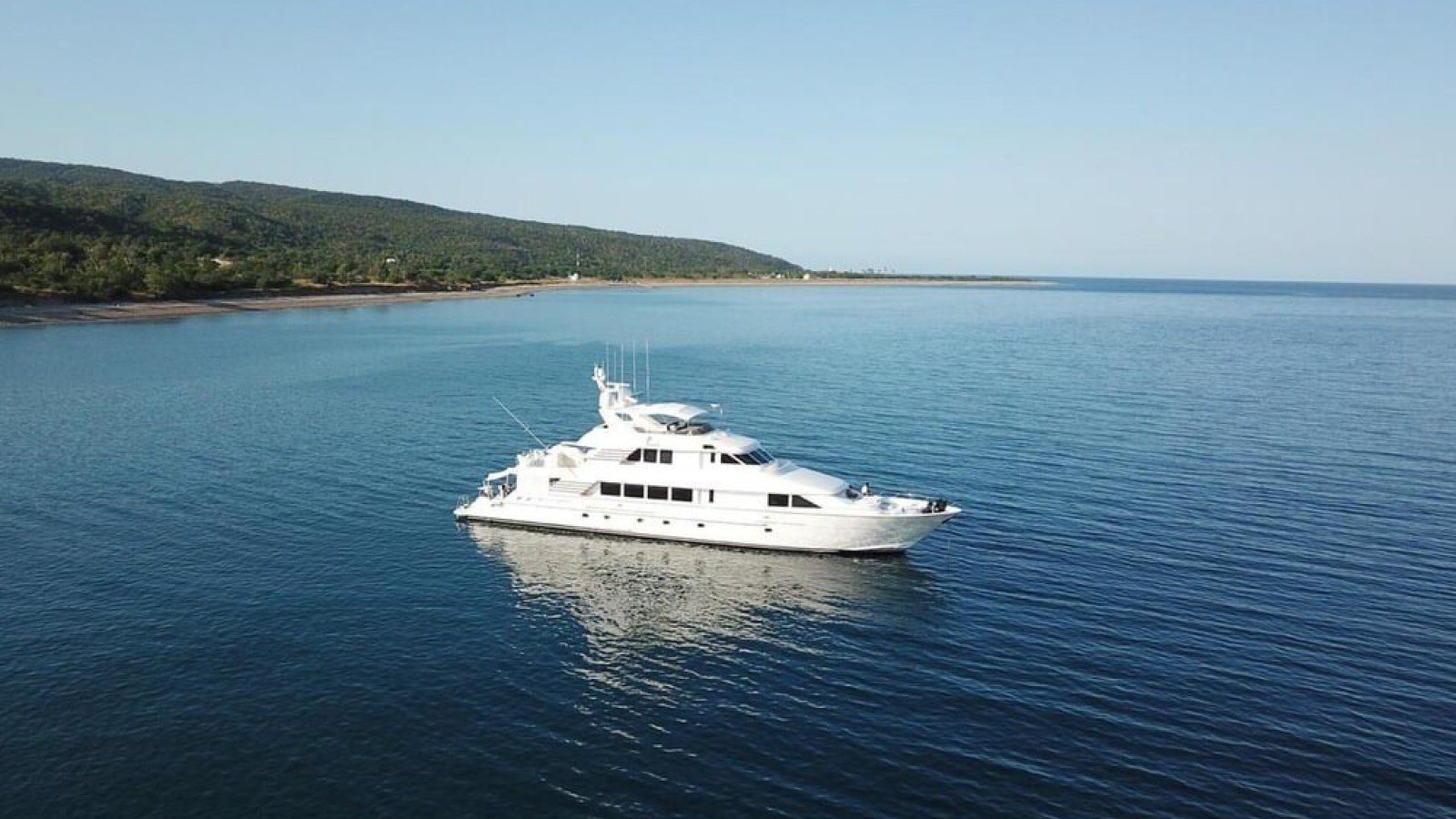 The Hatteras 122 superyacht at anchor in glassy water off the Banderas Bay coastline, a reminder that big boats are not always big-group boats